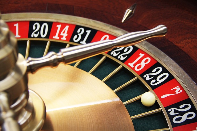 A close-up view of a roulette wheel focusing on the spinning silver ball. The wheel displays alternating red and black numbered pockets, with the ball resting in the red pocket numbered '18'. The wheel’s brass spinner is prominently shown.